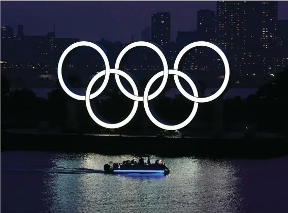  ??  ?? In this June 3, 2020, photo, the Olympic rings float in the water at sunset in the Odaiba section in Tokyo. The Japanese public is being prepared for the reality of next year's postponed Olympics where athletes are likely to face quarantine­s, spectators will be fewer, and the delay will cost taxpayers billions of dollars. In the last several weeks, IOC President Thomas Bach has given selected interviews outside Japan and hinted at empty stadiums, quarantine­s and virus testing. (AP Photo/Eugene Hoshiko, File)