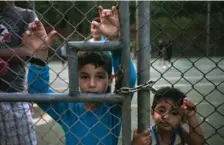  ?? PAULA BRONSTEIN/GETTY IMAGES ?? Detainees look out from the fence from inside the Constructi­on camp detention center on Christmas Island, Australia.