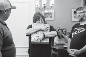  ?? Lisa Krantz / Staff photograph­er ?? Cheryl Estes, the mother of fire victim Dru Estes, hugs a box holding her late son’s sheet music after receiving it from San Marcos Fire Chief Les Stephens, left, on the one-year anniversar­y of the deadly fire at Iconic Village Apartments in San Marcos.