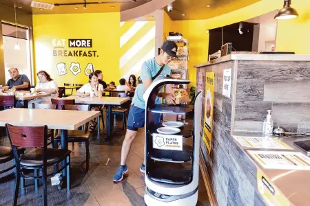  ?? Brittany Hosea-Small/Special to the Chronicle ?? Paul Y. picks up his order from the meal delivery robot this month at Egg Happiness in the Ulferts Center in Dublin.