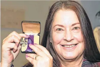  ?? JIM WELLS ■ POSTMEDIA ?? Tracey Scott shows a Memorial Cross medal which was among antique family photos returned in Calgary on Sunday. The photos and war medals were found in a donation to Goodwill and after some investigat­ion by Goodwill staff, the items were returned to Scott and her family.