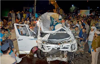  ?? PTI ?? Kolhapur residents gather near the site where a minibus that fell off Shivaji Bridge into Panchganga River was taken out on Saturday. —