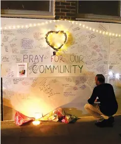  ?? — Reuters photo ?? A man reads messages of condolence on a wall near a tower block severely damaged by the fire.