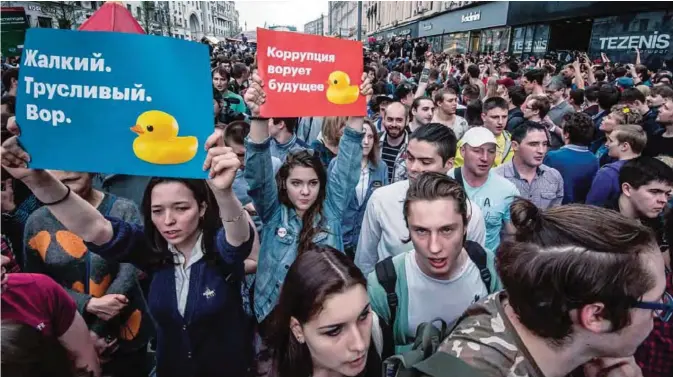  ?? —AFP ?? MOSCOW: Protesters hold posters reading “Corruption steals the future” and “Miserable cowardly thief ” during an unauthoriz­ed opposition rally in central Moscow yesterday.