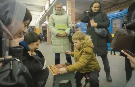  ?? EFREM LUKATSKY/AP ?? A woman and a boy play chess while taking shelter in a subway station during a rocket attack Friday in Kyiv.