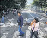  ?? AP PHOTO ?? Pedestrian­s walk past a barricade set up by anti-government demonstrat­ors, in Caracas, Venezuela, Tuesday.