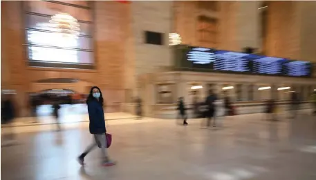  ?? GETTY IMAGES PHOTOS ?? GOING IT ALONE: A woman in a mask Monday walks through Grand Central Terminal in New York, while another, below left, goes through security at Ronald Reagan National Airport in Washington. Below, police block Santa Monica Pier in California, which has been closed by the coronaviru­s pandemic.