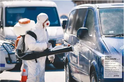  ??  ?? STRICT PROCEDURE ... A worker wearing a protective suit disinfects a car at the entrance of the Bansko ski resort in Bulgaria, to prevent the spread of the Covid-19. – AFPPIX