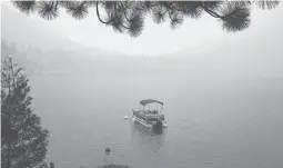  ?? RICH PEDRONCELL­I/AP ?? Smoke from the Caldor Fire shrouds Fallen Leaf Lake on Tuesday near South Lake Tahoe, Calif. The massive wildfire has scorched more than 190 square miles.