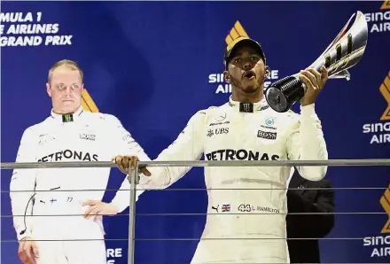  ?? — AP ?? Huge leap: Mercedes driver Lewis Hamilton (right) of Britain celebratin­g on the podium after winning the Singapore Grand Prix yesterday. Mercedes teammate Valtteri Bottas of Finland looks on after finishing third.