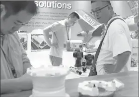  ?? AP Photo/Andy Wong ?? Trade: In this Sept. 20, 2017, photo, visitors look at aircraft component parts on display near a screen showing the China's flag raising ceremony, at Aviation Expo China in Beijing. China On Wednesday vowed to take measures of the "same strength" in...