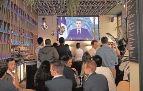  ?? // EFE ?? Clientes de un bar en París siguen ayer el discurso por televisión del presidente