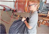  ??  ?? Jax Sealey, 11, from Butler, picks up a bag of cans he collects in his garage before scrapping them for fundraisin­g money.