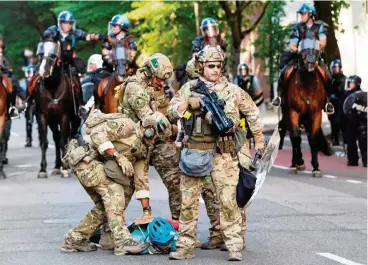  ??  ?? Militärpol­izisten haben in der Nähe des Weißen Hauses einen Demonstran­ten zu Boden gerungen.
FOTO: AFP