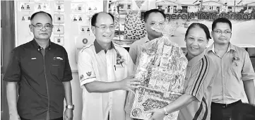  ??  ?? Gerawat (second left) presents a hamper to the captain of the winning mini-sports team at the function. On the assemblyma­n’s right is Joseph.