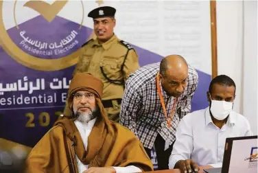  ?? Libyan High National Elections Commission ?? Seif al-Islam (left), the son of late Libyan dictator Moammar Khadafy, registers his candidacy for the country’s presidenti­al election in the southern town of Sabha. The election is planned for Dec. 24.