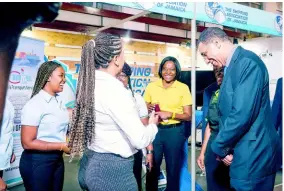  ?? ?? Prime Minister of Jamaica Andrew Holness (right) shares a light moment with Shipping Associatio­n of Jamaica exhibitors at their booth at Expo Jamaica 2023.