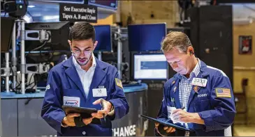  ?? ?? Traders Orel Partush (left) and Robert Charmak work Friday on the New York Stock Exchange floor. Stocks fell sharply Friday after getting hammered by data showing inflation is getting worse.