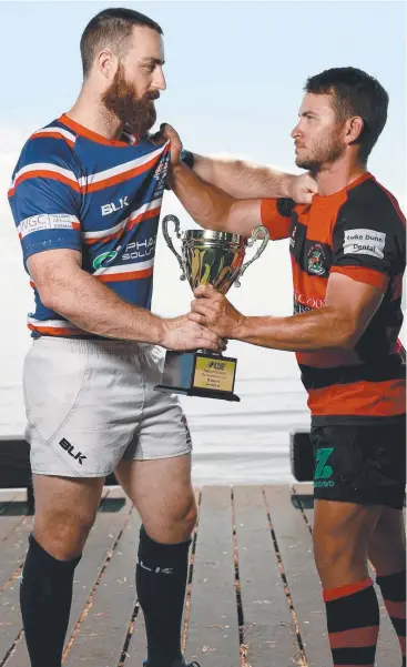  ?? Picture: MARC MCCORMACK ?? BATTLE LINES: Barron Trinity Bulls captain Cameron Thomson and JCU Mariners captain Tahl Young get a grip on the trophy ahead of today’s FNQ Rugby grand final.