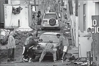  ??  ?? Neighbors come together to move a car by hand Thursday in San Juan, Puerto Rico.