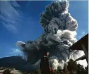  ?? AFP ?? Left: A man watches as Mount Sinabung releases volcanic material into the air in Tiga Serangkai, North Sumatra, Indonesia.
Far left: A technician checking a control panel at the Wayang Windu geothermal power station.