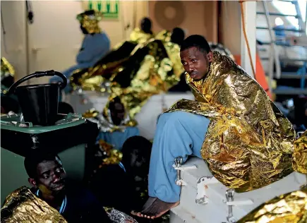  ?? REUTERS ?? Migrants from sub-Saharan Africa rest under thermal blankets aboard the Golfo Azzurro, a rescue boat operated by Spanish NGO Proactiva Open Arms, after they were picked up off the Libyan coast yesterday. The organisati­on has rescued more than 200 migrants in the past two days.