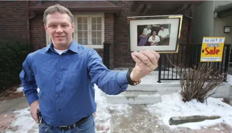  ??  ?? Homeowner Steve Adams hold up a 1992 picture of his family. The family has held the home at 505 Davenport Rd. for three generation­s.