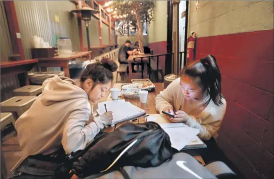  ?? Photograph­s by Gary Coronado Los Angeles Times ?? MY LY, left, and Vinnie Ta, sophomores at Lincoln High School, work on their homework together at the Heights Deli & Bottle Shop on North Broadway last month.