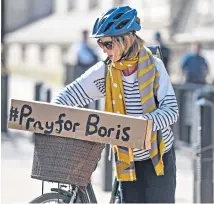  ??  ?? Sign of the times A cyclist rode around Westminste­r with a placard urging people to pray for Boris Johnson’s recovery from Covid-19 after he was admitted to hospital.