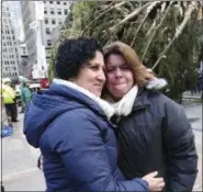  ?? AP PHOTO/JULIE WALKER ?? Lissette Gutierrez, left, hugs her wife, Shirley Figueroa, with the 72-foot-tall Norway spruce that the couple donated in the background Saturday in New York. The tree was hoisted into position by crane after making the 60 mile trip from the couple’s Wallkill, N.Y. home and will become the 2018 Rockefelle­r Center Christmas tree.