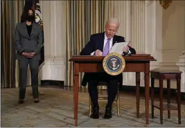  ?? EVAN VUCCI — THE ASSOCIATED PRESS ?? President Joe Biden signs executive orders in the State Dining Room of the White House in Washington on Tuesday. Vice President Kamala Harris listens at left.