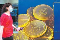  ?? AP-Yonhap ?? A woman walks past an advertisem­ent for the Bitcoin cryptocurr­ency in Hong Kong in this June 1 file photo.