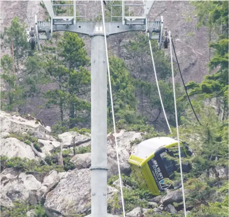  ?? DARRYL DYCK/THE CANADIAN PRESS ?? A gondola car rests on its side on the mountain after a cable was cut around 4 a.m. Saturday at the Sea to Sky Gondola
in Squamish, B.C., causing cable cars to crash to the ground below.