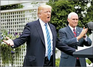  ?? AP/EVAN VUCCI ?? Vice President Mike Pence applauds Monday as President Donald Trump arrives in the Kennedy Garden of the White House in Washington to speak to the Independen­t Community Bankers Associatio­n.