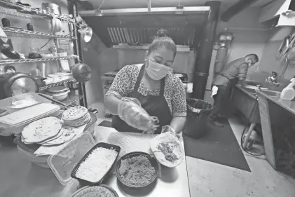 ?? SHAWN DOWD/ROCHESTER DEMOCRAT AND CHRONICLE FILE PHOTO ?? Minerva Martinez fills a quesadilla with shredded chicken as she makes an order in the kitchen at Peach Blossom Mexican Restaurant. Martinez and her son Marco Murcia serve dishes that are true to their native Mexico at their location on East Main Street in downtown Rochester.