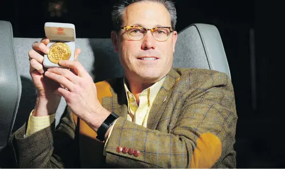  ?? AL CHAREST ?? Calgary 2026 chair Scott Hutcheson on Monday holds up a gold medal given to him by his father Bob, who received it after the 1988 Winter Olympics in Calgary for volunteeri­ng.