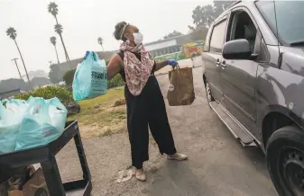  ?? Nick Otto / Special to The Chronicle ?? Hope Williams, a family liaison for the S.F. Unified School District, hands out student meals and groceries to a resident on Treasure Island, where many families were formerly homeless.