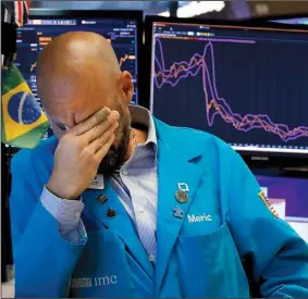  ?? AP/RICHARD DREW ?? Specialist Meric Greenbaum takes a moment Friday on the floor of the New York Stock Exchange as stocks dived in a sweeping sell-off.