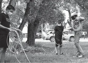  ??  ?? Solly Levine, wrangler, right, helps two young guests, Luther Joly, 16, left, and his 12- year- old brother, Adam, practice their roping during their stay in July at Zapata Ranch in Mosca.