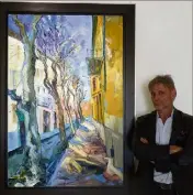  ??  ?? Denis Ribas devant l’une des deux plus grandes toiles de l’exposition. Elle représente la rue du Général Gallieni à Menton.(Photo M.C.)