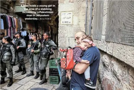  ?? / REUTERS ?? A man holds a young girl in the area of a stabbing incident by a Palestinia­n man in Jerusalem yesterday.