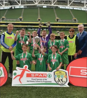  ??  ?? We are the Champions! Scoil Mhuire Gan Smal players celebrate with coach John Lavin after winning the FAI School 5s National Finals.