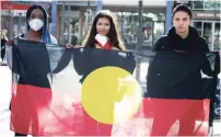  ?? ROD MCGUIRK THE ASSOCIATED PRESS ?? School friends Oluwatobi Odusote, left, Jan Usha and Rhyse Morgan hold an Aboriginal flag in Canberra, Australia, on Friday.