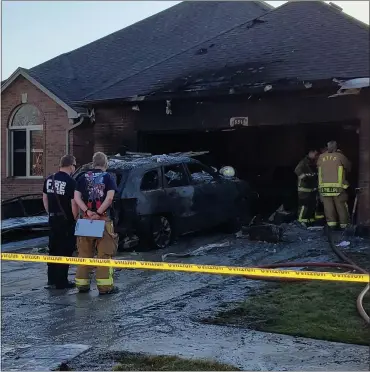  ?? DAVE ANGELL — FOR THE MACOMB DAILY ?? Macomb Township fire crews examine the damage caused by an air compressor that blew up in the garage of this house on Frost Drive.