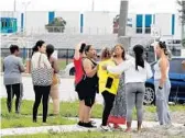  ?? MIKE STOCKER/SUN SENTINEL ?? Parents gather across the street from Coral Springs High School on Friday. A security crew had spotted a student by a fence and alerted police to a possible intruder.