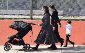  ?? Kathy Willens / Associated Press ?? Two women walk with children during the Jewish holiday of Sukkot on Sunday in the Borough Park neighborho­od of the Brooklyn borough of New York. Amid a new surge of COVID-19 in New York’s Orthodox Jewish communitie­s, many residents are reviving health measures that some had abandoned over the summer — social distancing, wearing masks. For many, there’s also a return of anger: They feel the city is singling them out for criticism that other groups avoid.