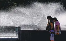  ?? Luis Sinco Los Angeles Times ?? PASSERSBY ENJOY some cool mist from a fountain at Cerritos Civic Center. Hot, dry conditions continue to hamper firefighti­ng efforts throughout the state.