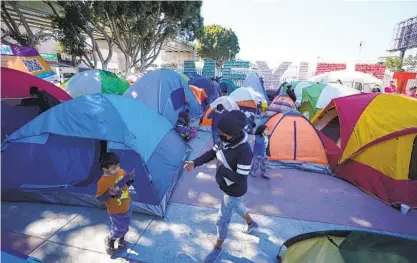  ?? ALEJANDRO TAMAYO U-T PHOTOS ?? Asylum seekers have set up about 50 tents at the Chaparral Plaza on the Tijuana side of the U.S.-Mexico border crossing. People began coming after the new administra­tion said it would process some people seeking refuge.