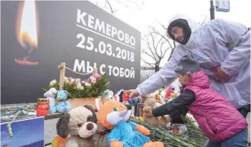  ?? — AFP ?? A girl places a teddy bear at a makeshift memorial in tribute to the victims of a Siberian shopping mall fire at Manezhnaya Square in downtown Moscow on Tuesday.