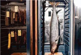  ?? ?? Various charcuteri­e (left) and a whole white seabass hang in dry agers at Aphotic in San Francisco.